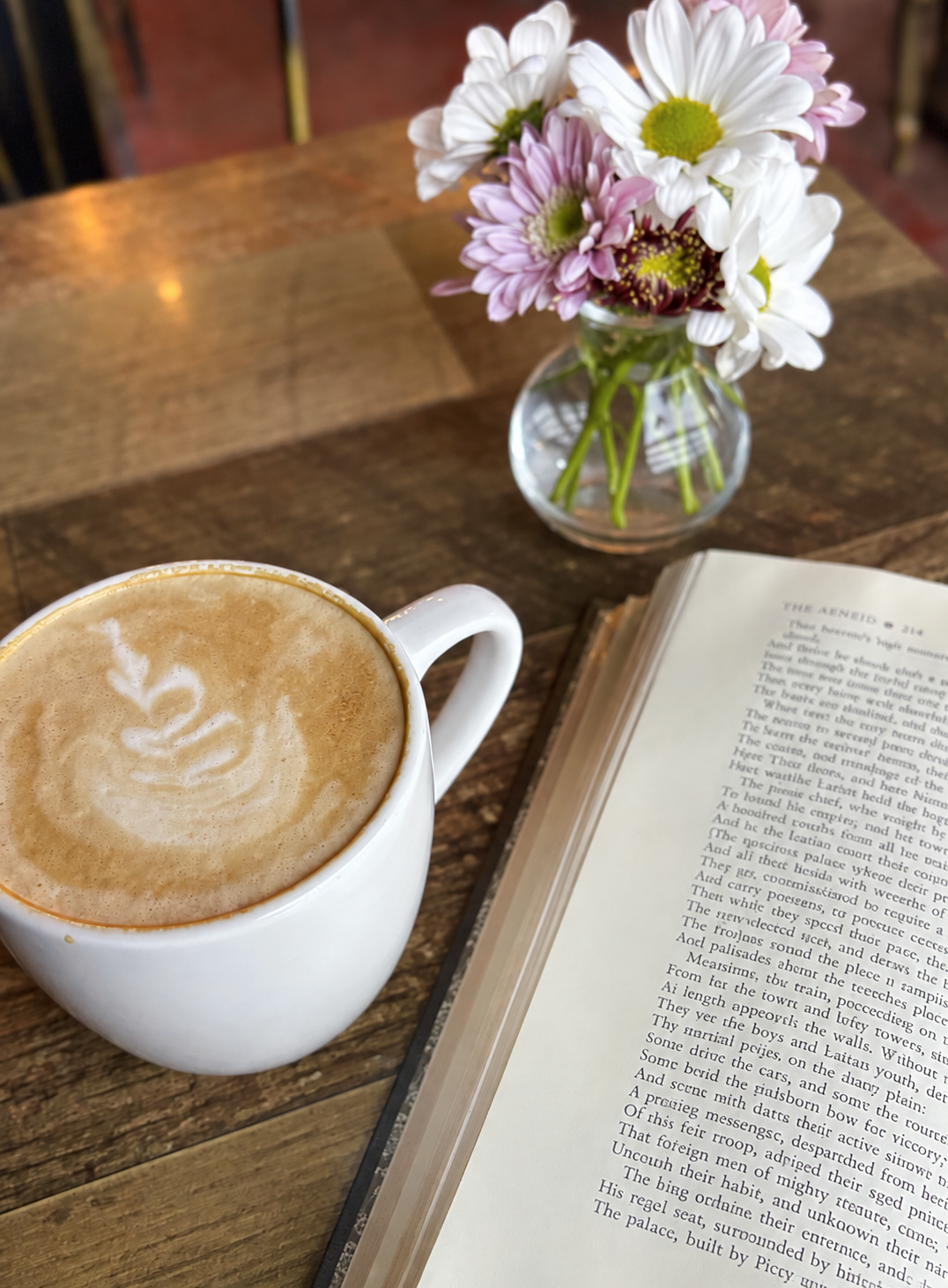 Coffee beside a book and flowers at STIR